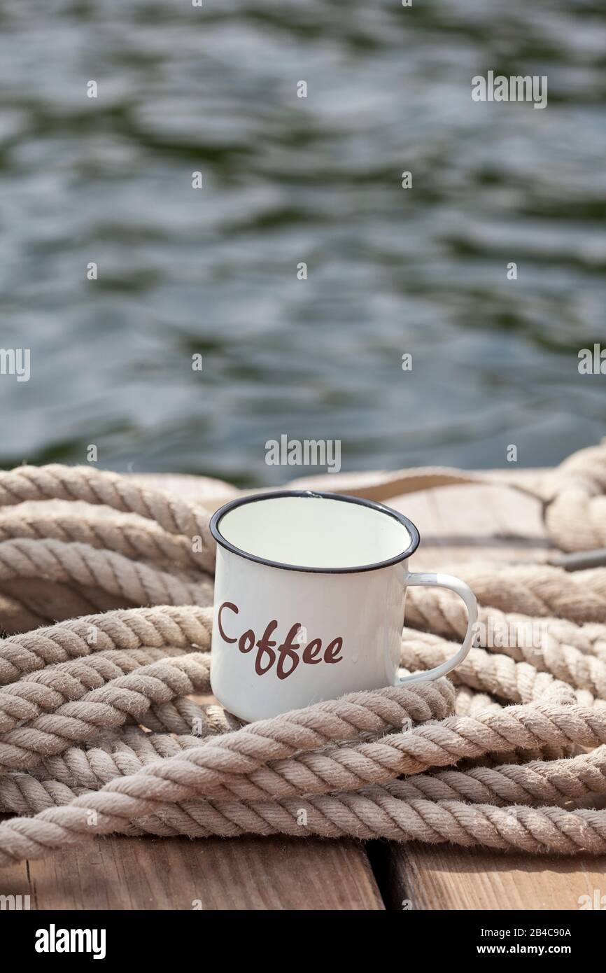 https://c8.alamy.com/comp/2B4C90A/rustic-enamel-coffee-cup-with-word-coffee-on-it-and-decorative-thick-rope-on-a-wooden-jetty-at-the-waters-edge-2B4C90A.jpg
