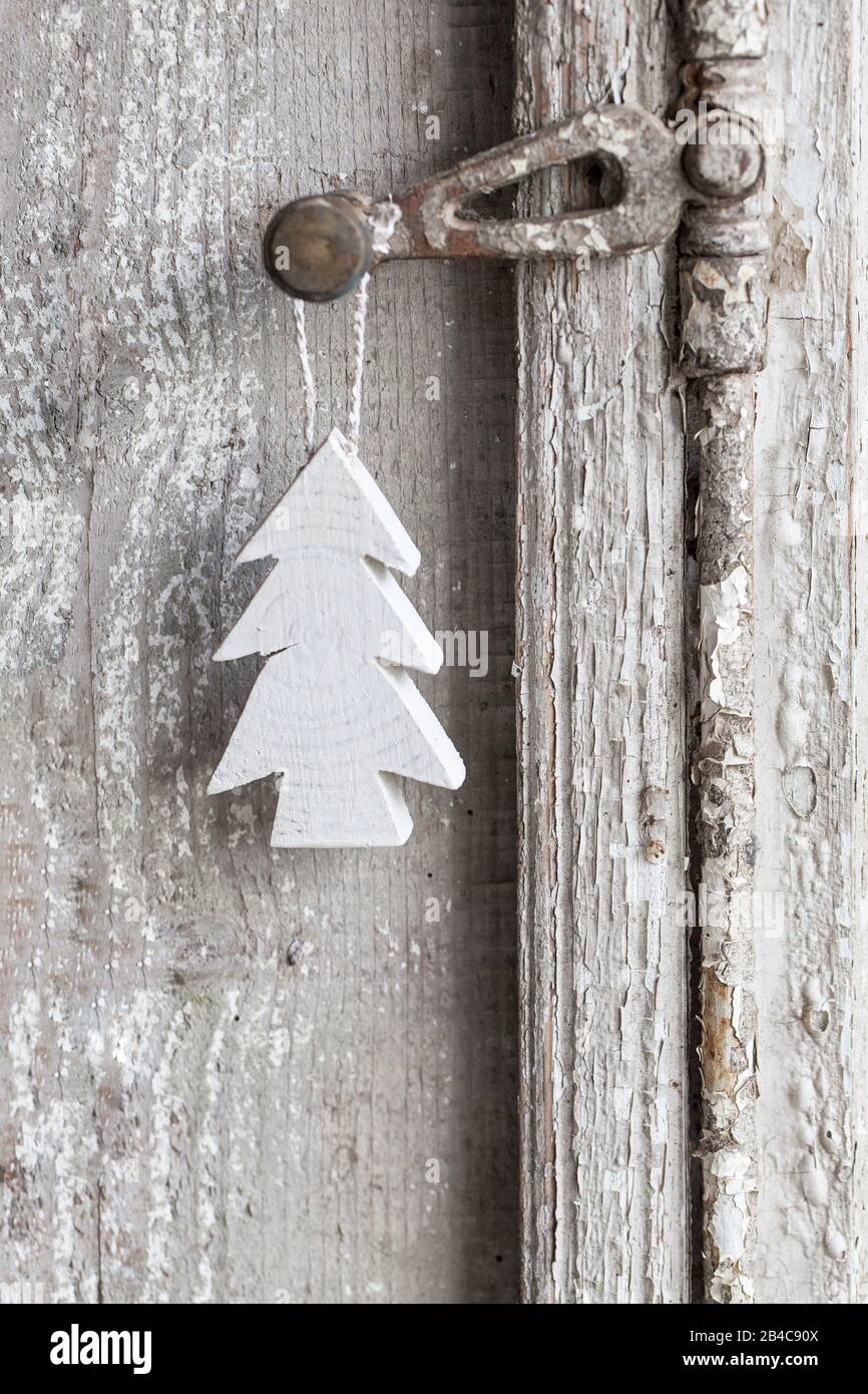 simple little Christmas tree ornament hanging on old window handle Stock Photo
