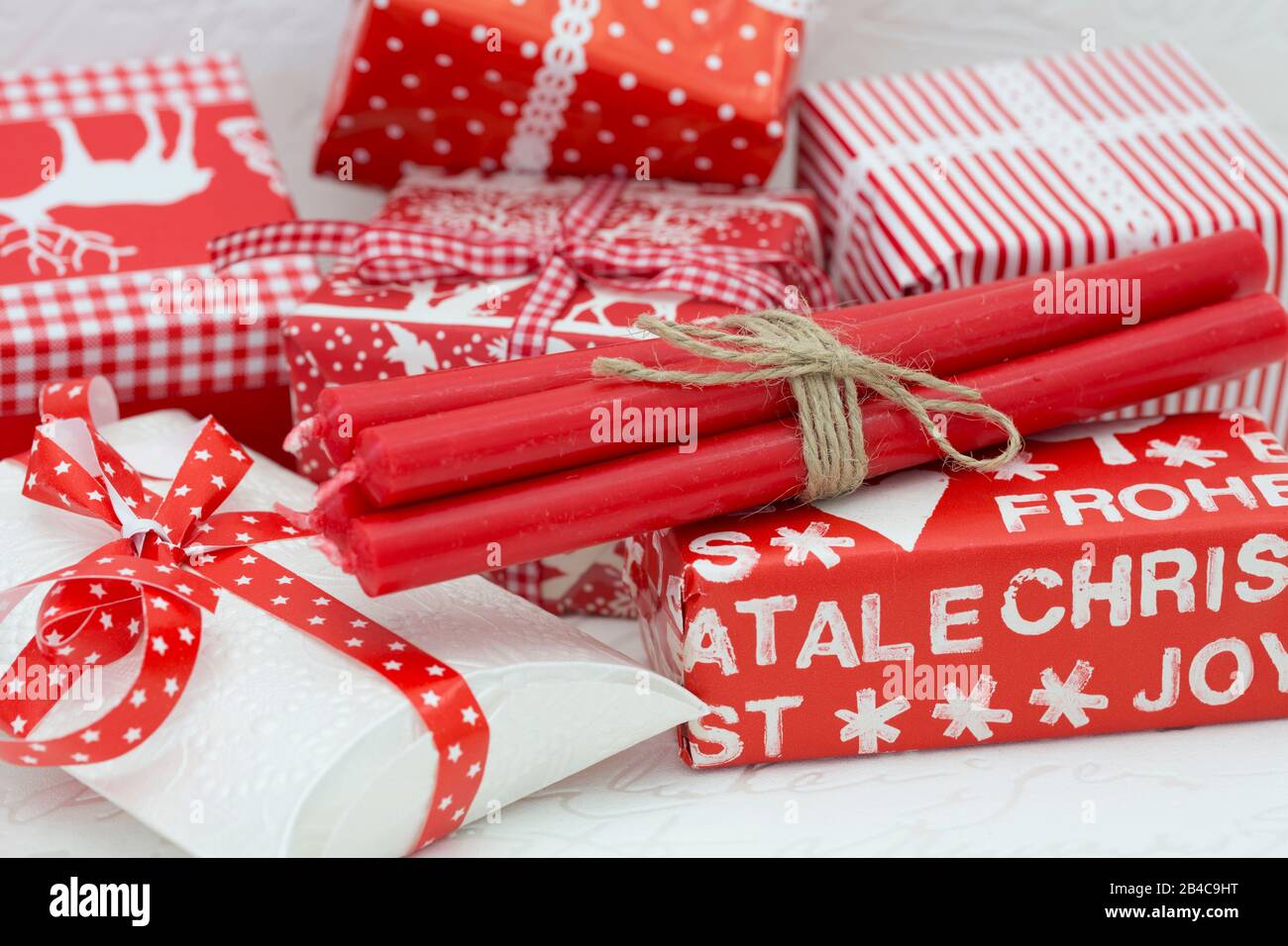 Bundle of red Christmas candles on many gift boxes wrapped in red white paper Stock Photo