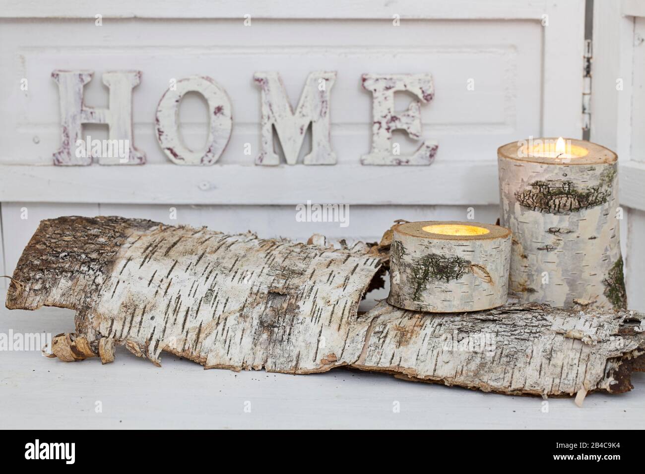 rustic winter deocoration in a white interior, with with homemade birch candle holders and word home in wooden letters Stock Photo