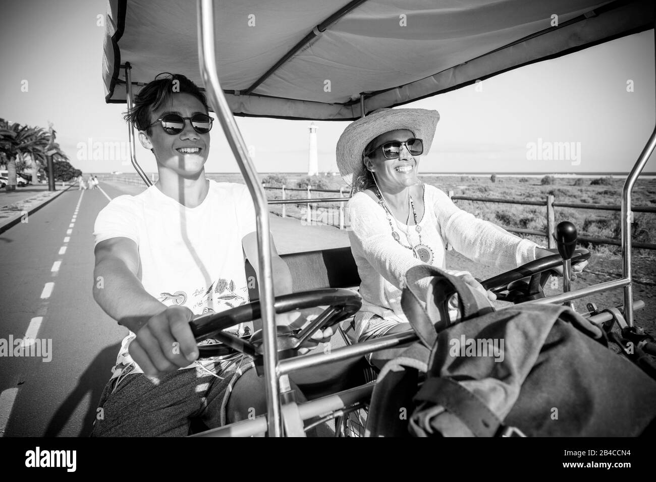 couple of mother and son having fun together very happy sitted on a doble bike and riding it together - vacation and travelers lifestyle concept -diversity and mixed ages generations have fun Stock Photo