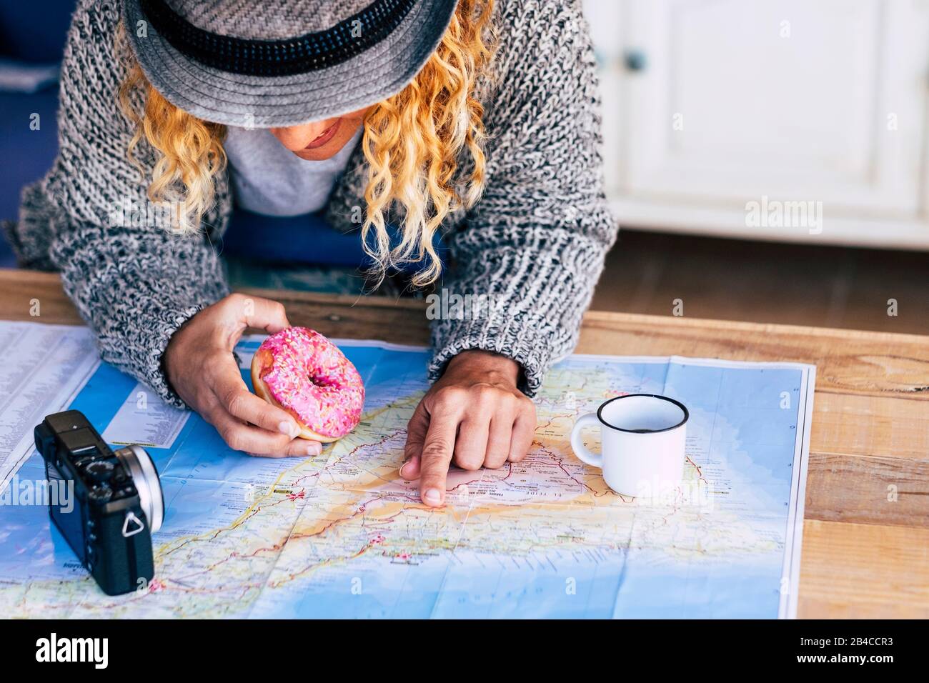 Alternative hipster travel young girl planning her next adventure trip on a island - paper old map on a wooden table and vintage camera - breakfast time for travelers people Stock Photo