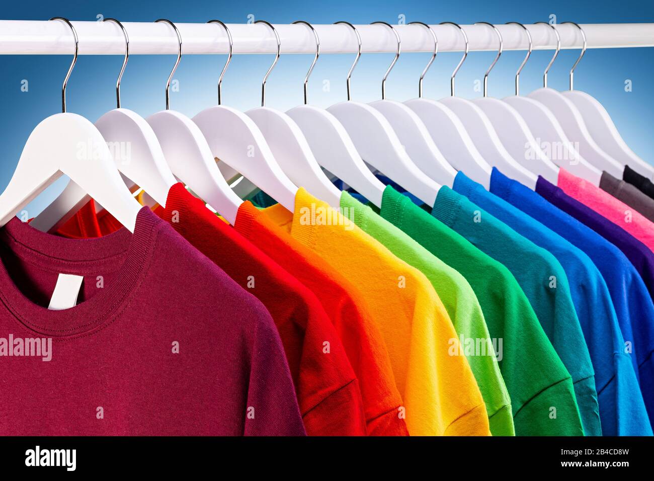 https://c8.alamy.com/comp/2B4CD8W/row-of-many-fresh-new-fabric-cotton-t-shirts-in-colorful-rainbow-colors-hangng-on-clothes-rail-in-wrdrobe-various-colored-shirts-on-blue-white-backgr-2B4CD8W.jpg