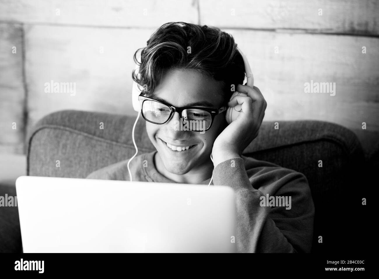 Black and white technoloy indoor activity with cute young teenager people with personal laptop computer and headphones  for music or study speech podcast - modern student lifestyle with internet connection Stock Photo