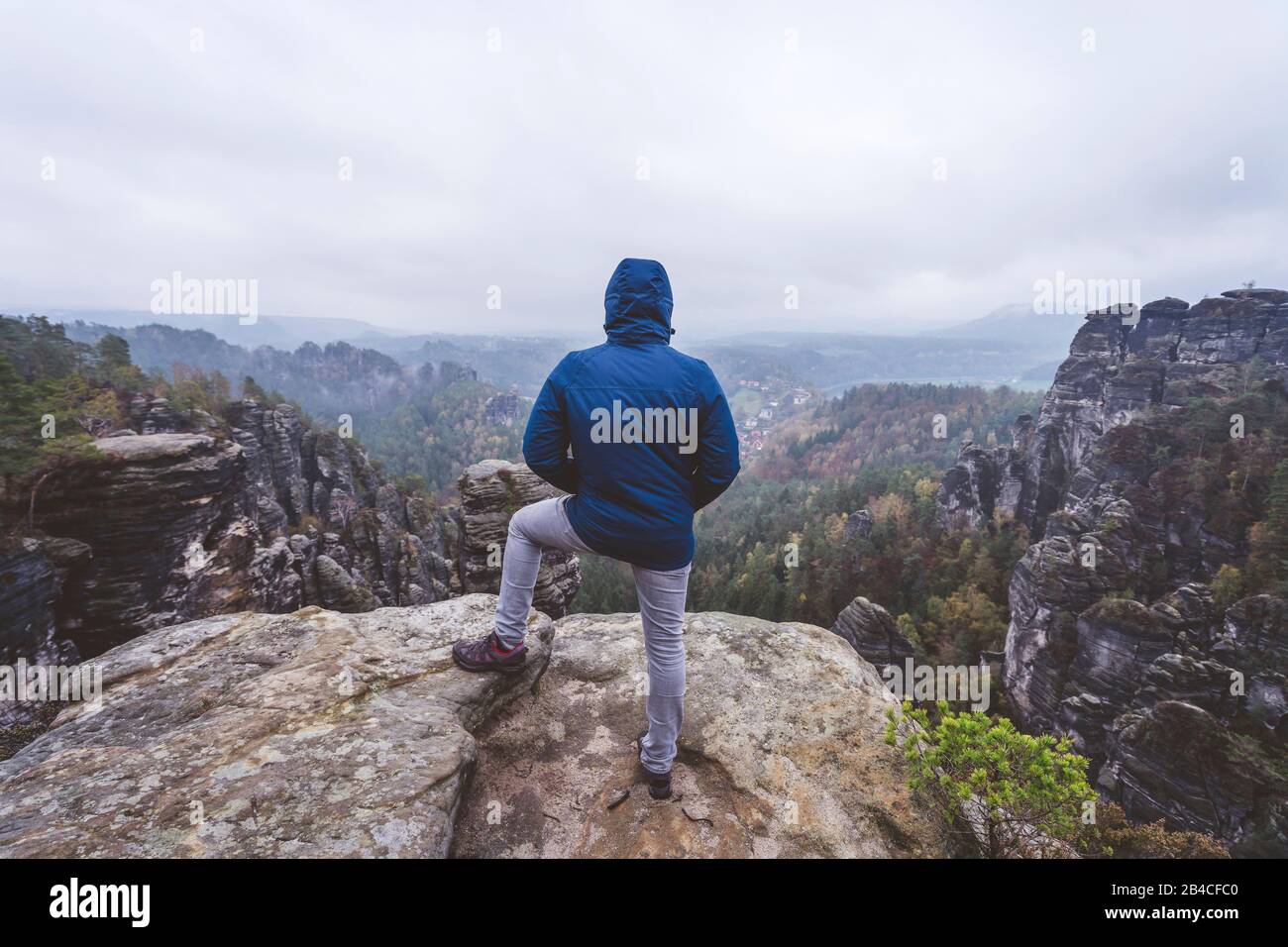 Wanderer steht auf dem Gipfel eines Berges, genießt die Aussicht über Berge und Wälder im Tal, Reise-Lifestyle-Abenteuer-Konzept Stock Photo