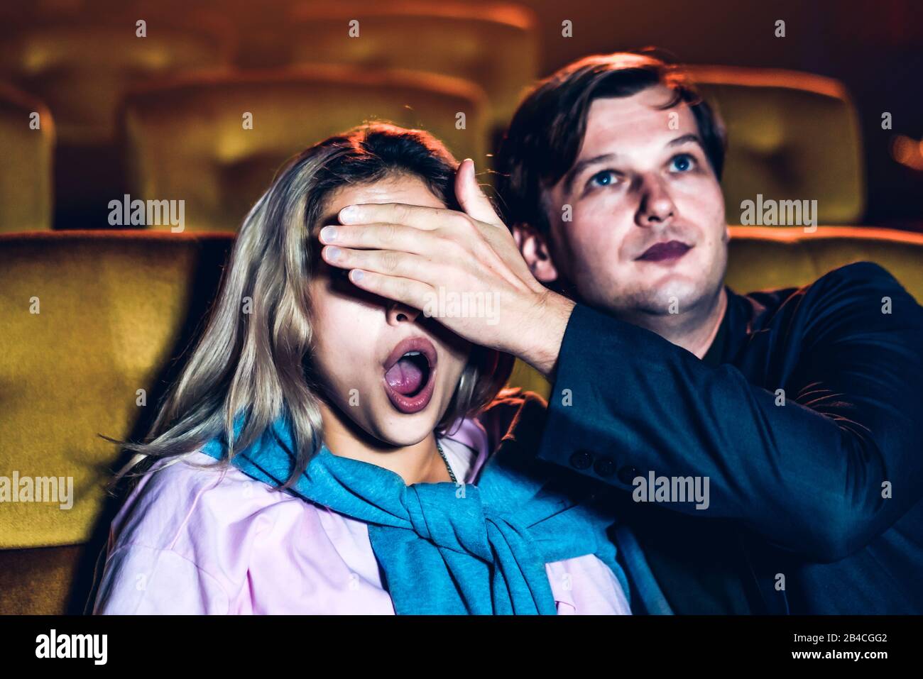 A couple watching a thriller movie in the cinema, Men use their hands to  close his girlfriend's eyes Stock Photo - Alamy