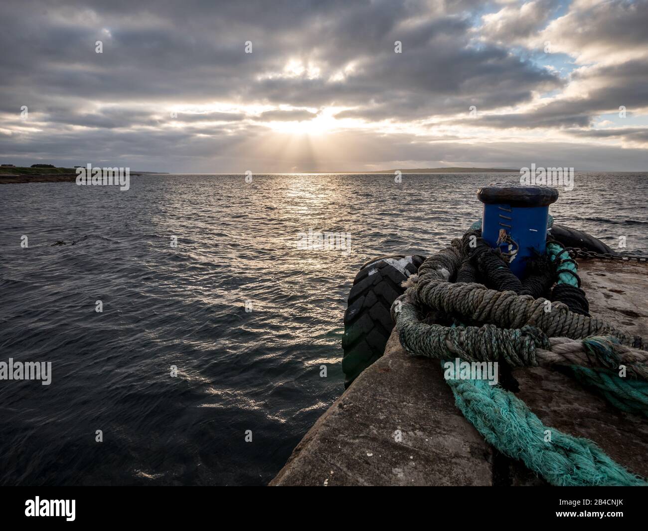 Dusk and the Orkney Islands. A view north from John O'Groats harbour towards Stroma and the Orkneys with sunlight breaking through the cloud cover. Stock Photo
