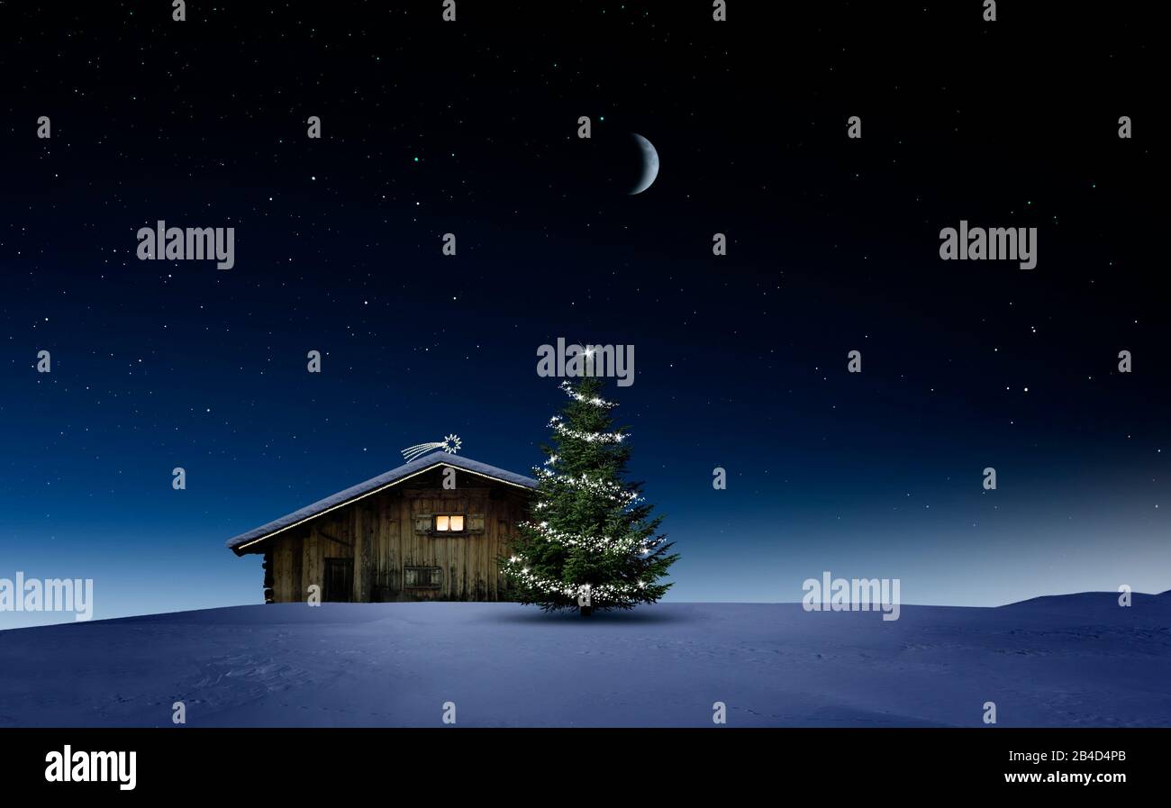 Shining, glowing Christmas tree in the snow near a wooden hut with a glowing window [M] Stock Photo