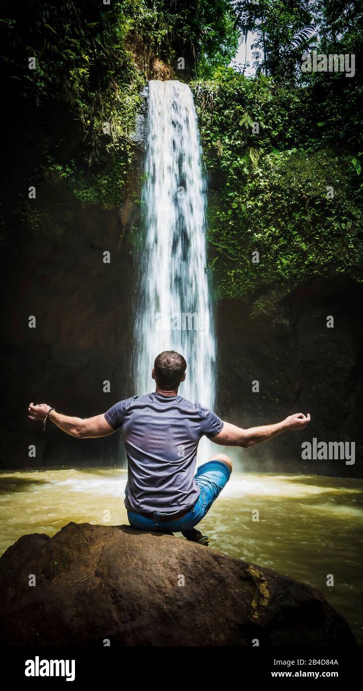 Man meditating in front of waterfall near Ubud, Bali, Indonesia. Stock Photo