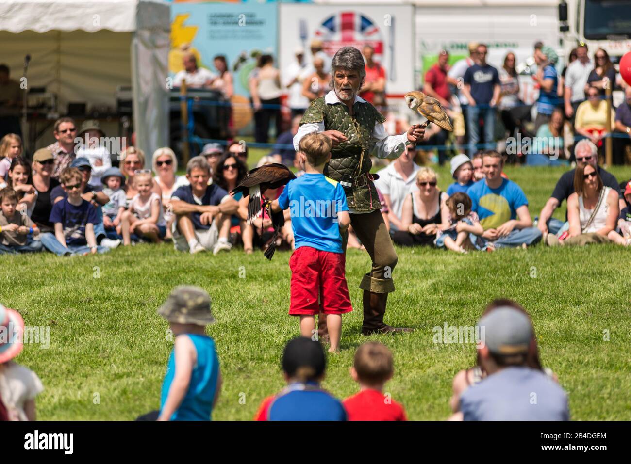A male falconer with owl and young boy with crowd, Cambridgeshire County Show, United Kingdom Stock Photo