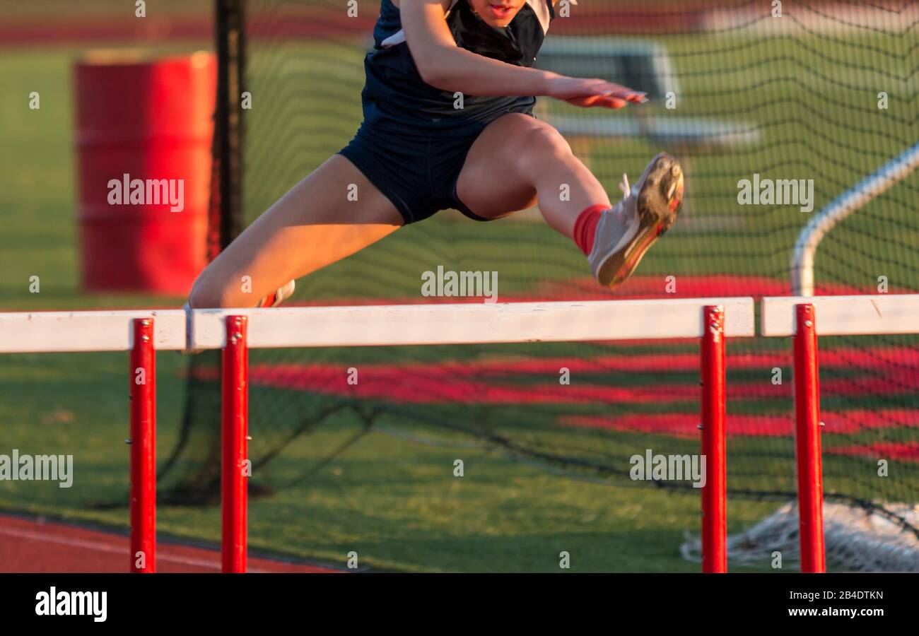 A high school girl is running the hurdles during a track and field