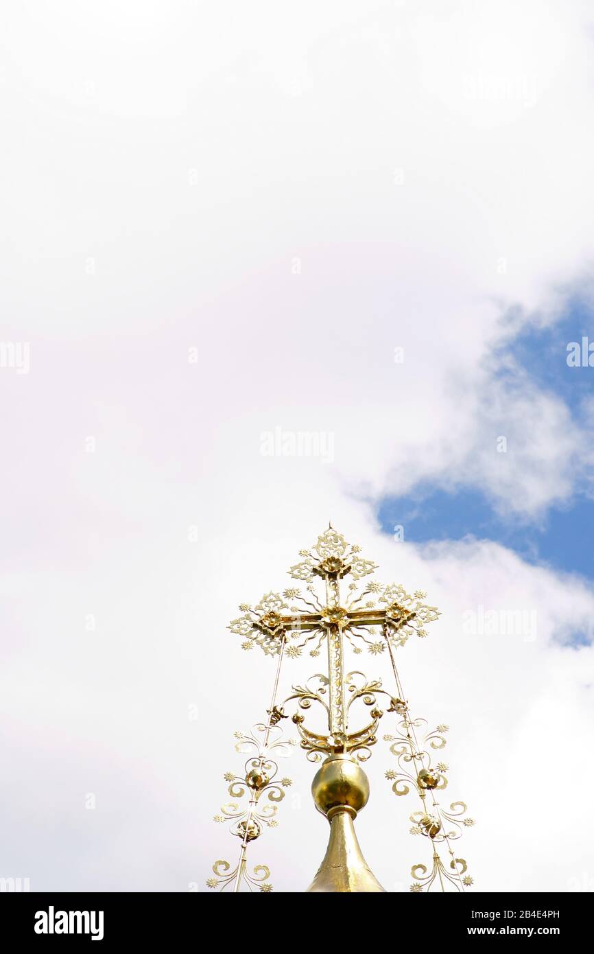 The ornate golden cross of a Russian chapel in front of a blue sky. Stock Photo