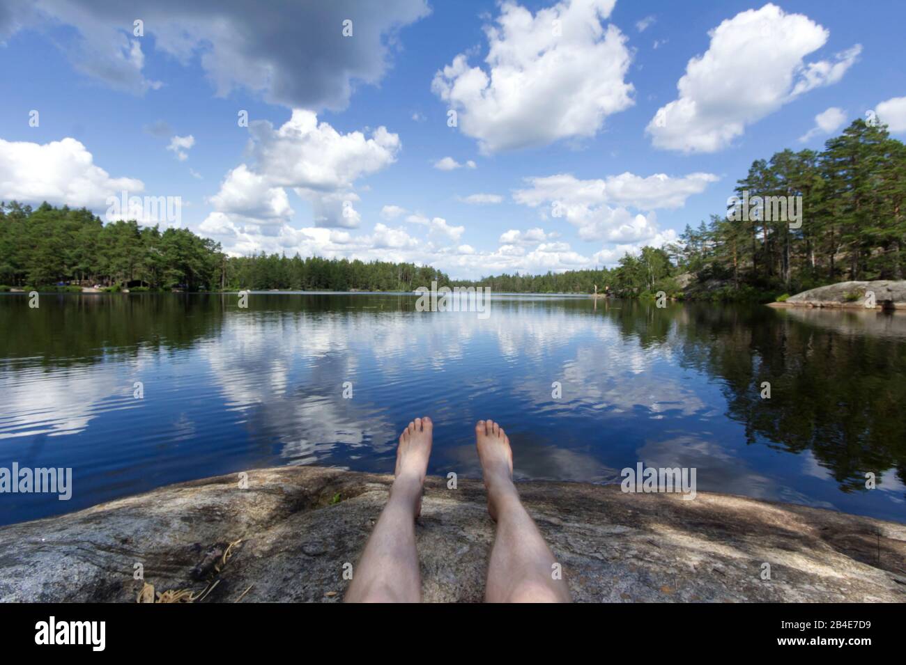 Person relaxes on a Scandinavian lake, surrounded by pine trees, Sweden, Tyresta National Park Stock Photo