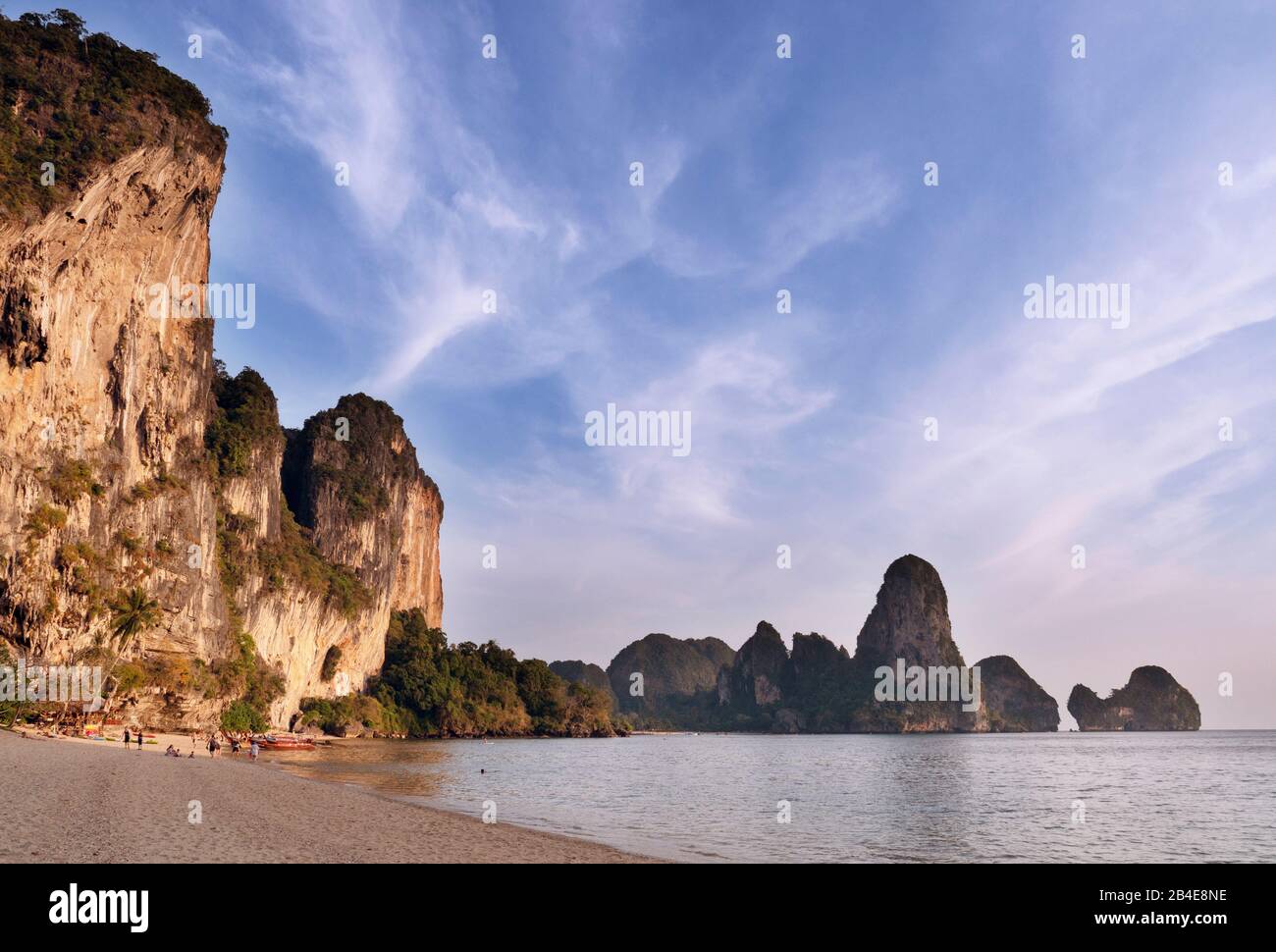 The rocks on Tonsai Beach are illuminated by the low sun. In the background Railay Beach Stock Photo