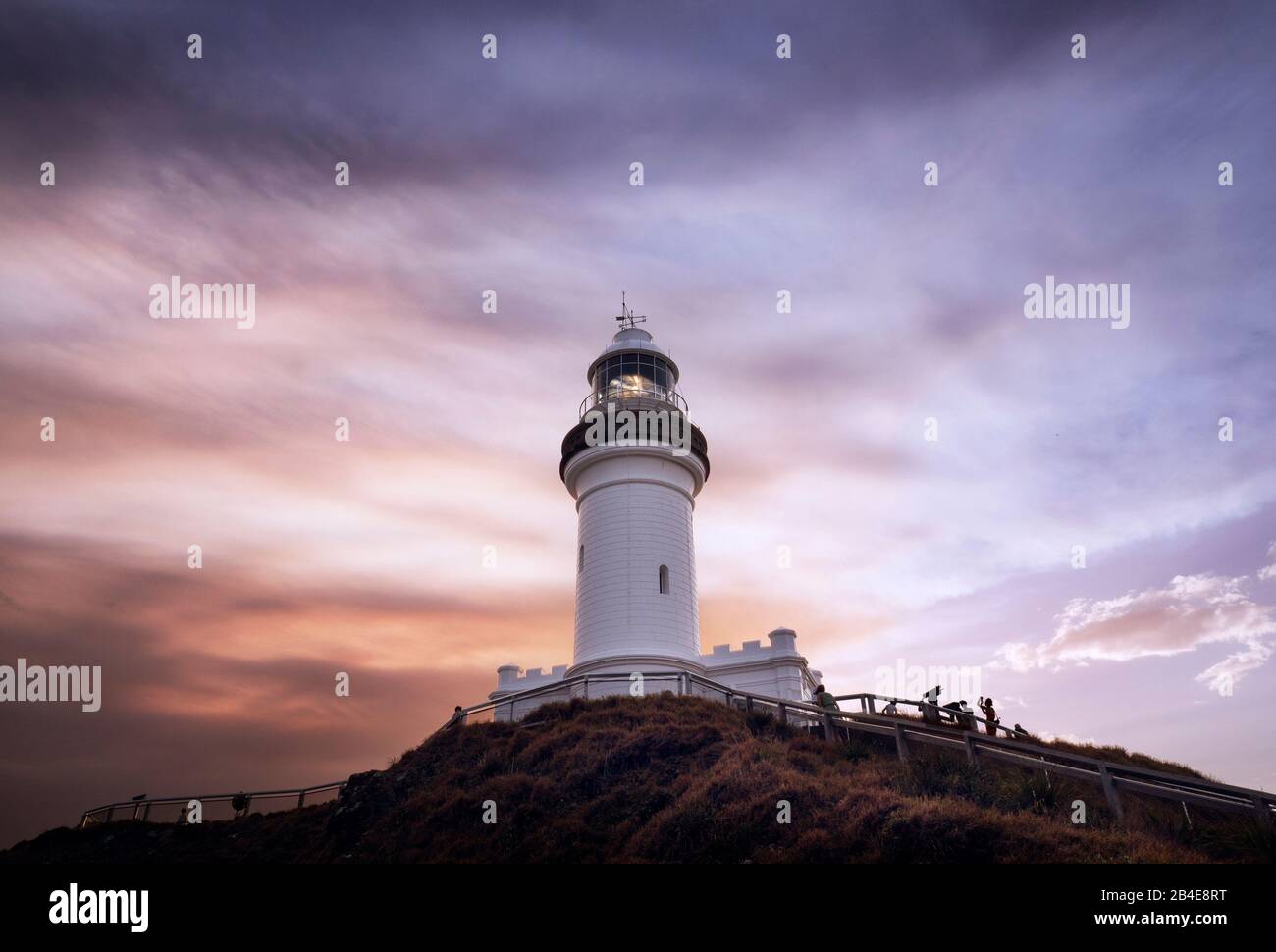 Cape Byron Lighthouse at sunset, seen from a lower observation deck. Dark clouds raise and color the sky red Stock Photo