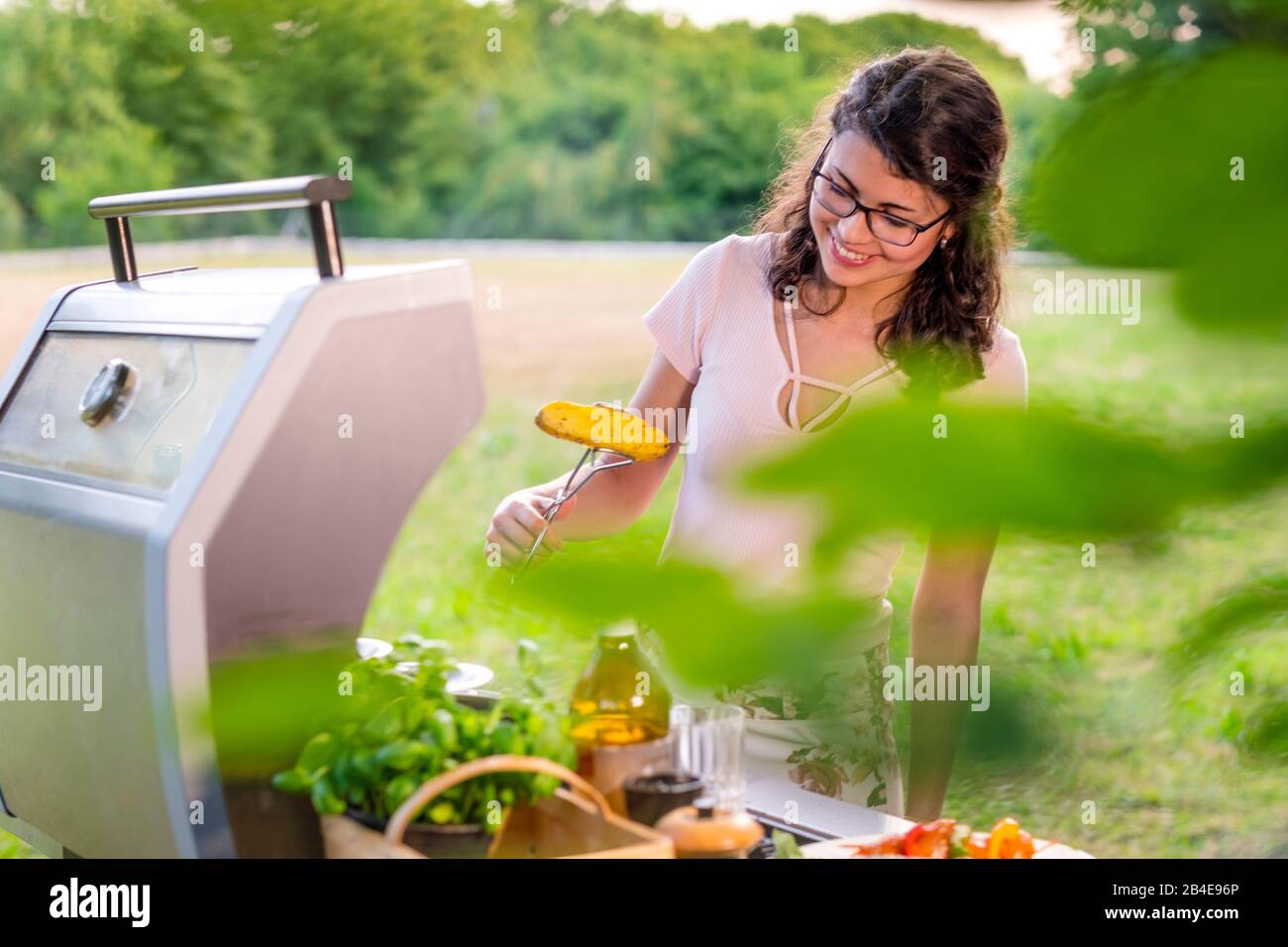 Junge Frau grillt im Garten, Grillfest Stock Photo