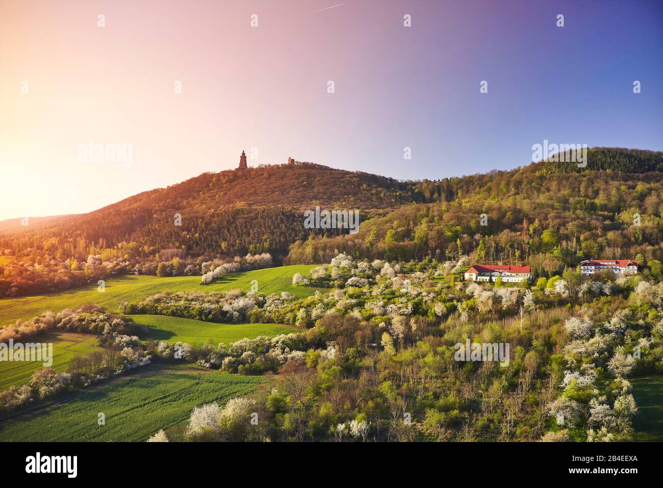 Germany, Thuringia, border to Saxony-Anhalt, blooming orchards, hills with the monument Kyffhäuser, Germany's third largest monument, radiant morning sun Stock Photo