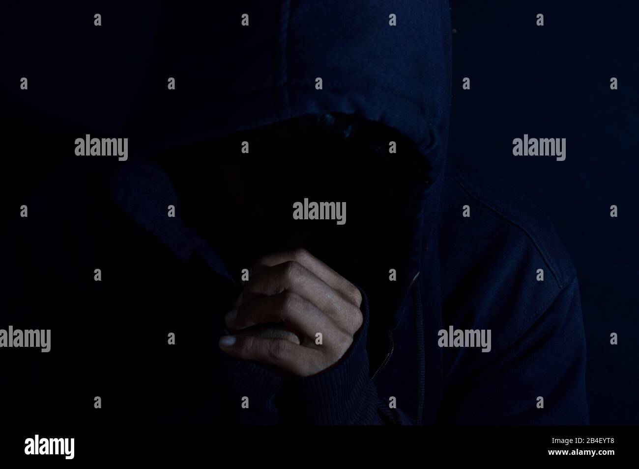 Young man worship and pray in cruch on dark black background. Christian faith or god concept. selective focus on finger Stock Photo