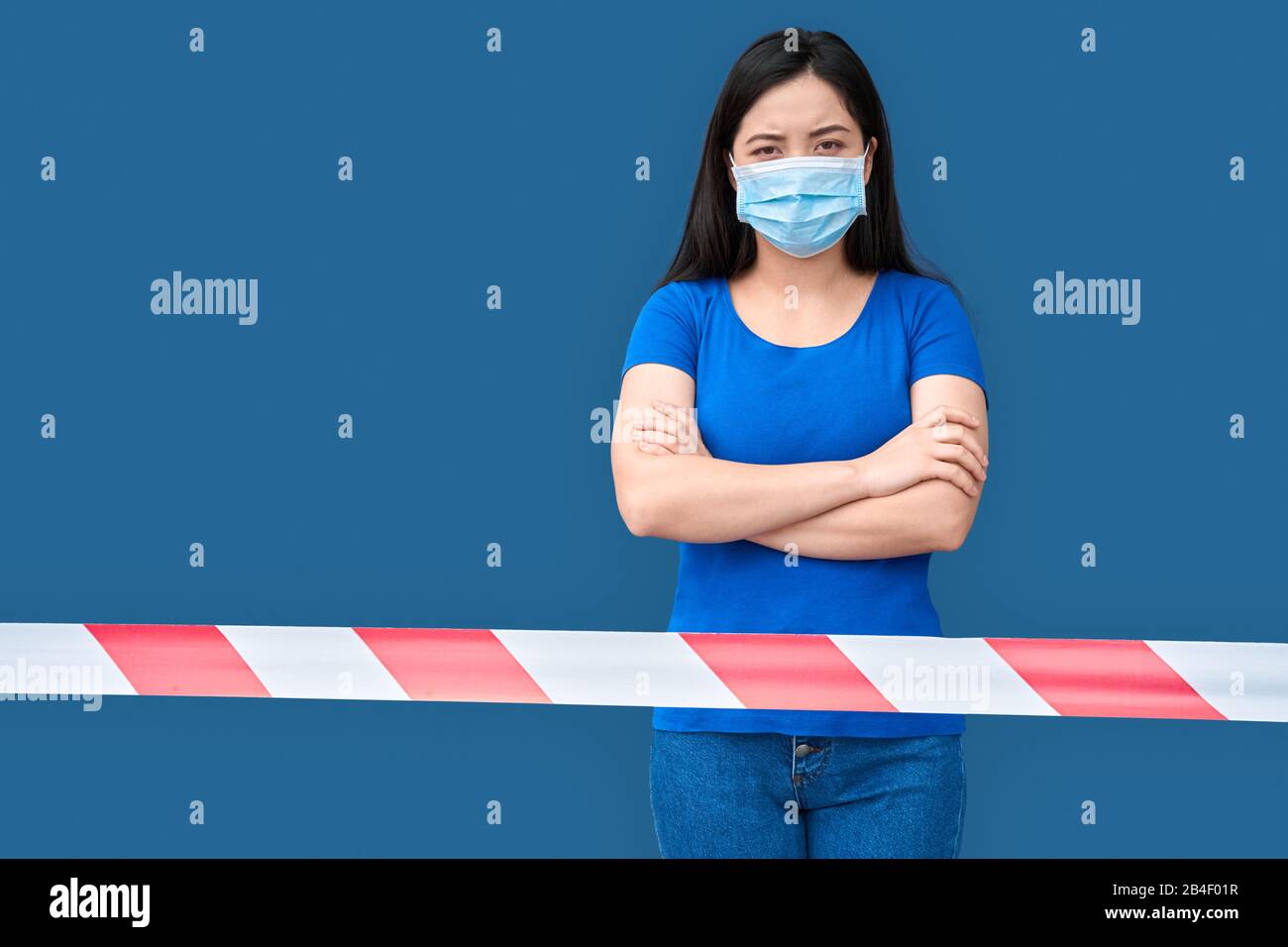 Young chinese woman wearing medical face mask standing isolated on blue  background behing warning red tape being on coronavirus quarantine crossed  han Stock Photo - Alamy