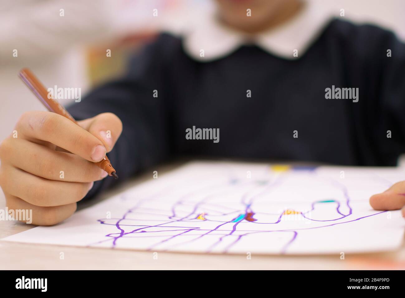 Child drawing abstract forms on a paper on vibrant colours. Introducing abstract form through the shadow of objects in art education class at school Stock Photo