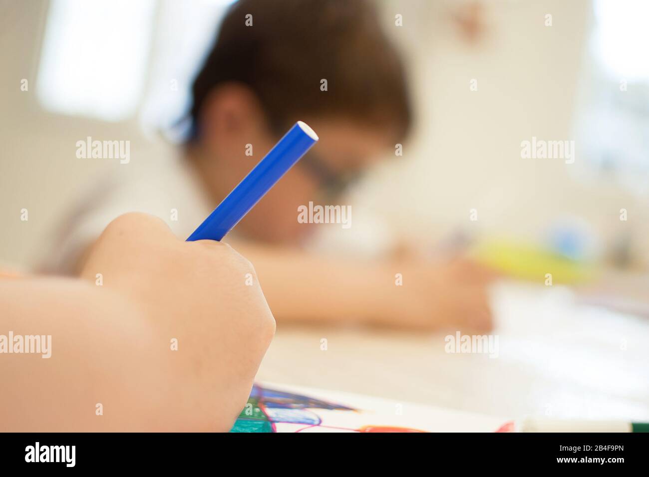 Child drawing abstract forms on a paper on vibrant colours. Introducing abstract form through the shadow of objects in art education class at school Stock Photo