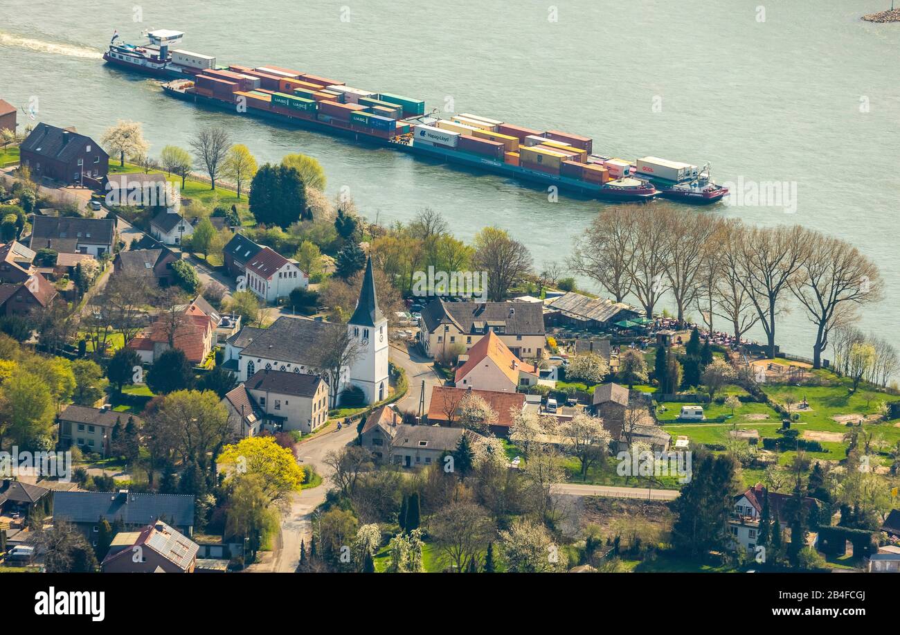 Aerial view of Götterswickerhamm am Rhein in Voerde in the state Nordrhein-Westfalen, Germany. Freight ship in front of the Rhine with the church Schinkelkirche Götterswickerhamm - Protestant parish Götterswickerhamm. Stock Photo