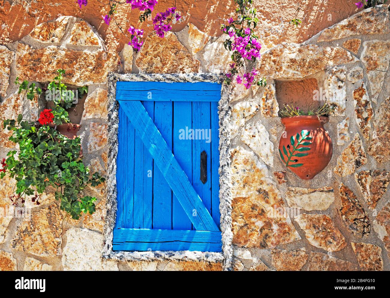 Colorful shutters and doors in stone house decorated with flower tubs, Greece Stock Photo