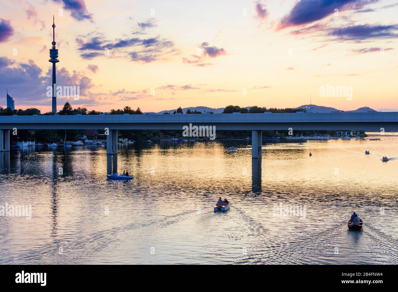 Wien / Vienna, oxbow lake river Alte Donau (Old Danube), sunset, tower Donauturm, bridge subway line 1, boat in 22. Donaustadt, Wien, Austria Stock Photo