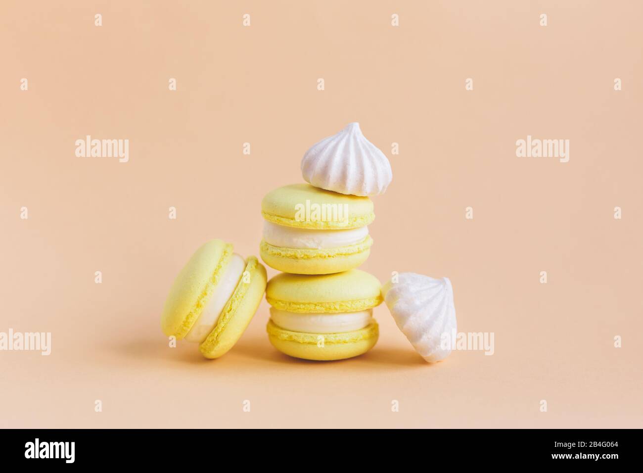 Yellow macarons and white marshmallows on a peach pastel background. Place for text. Stock Photo