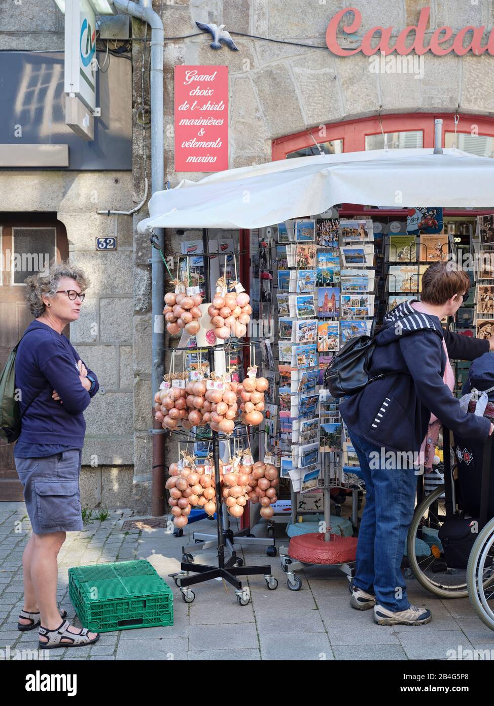 Touristen in Roscoff in der Bretagne, das für seine Zwiebeln bekannt ist, vor einem Souvenirgeschäft. Stock Photo