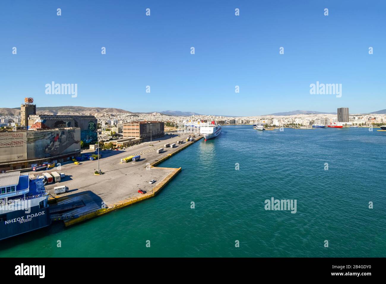 Cruise ships and ferry dock at the harbor port of Piraeus on a sunny summer day with the city of Athens Greece in view. Stock Photo