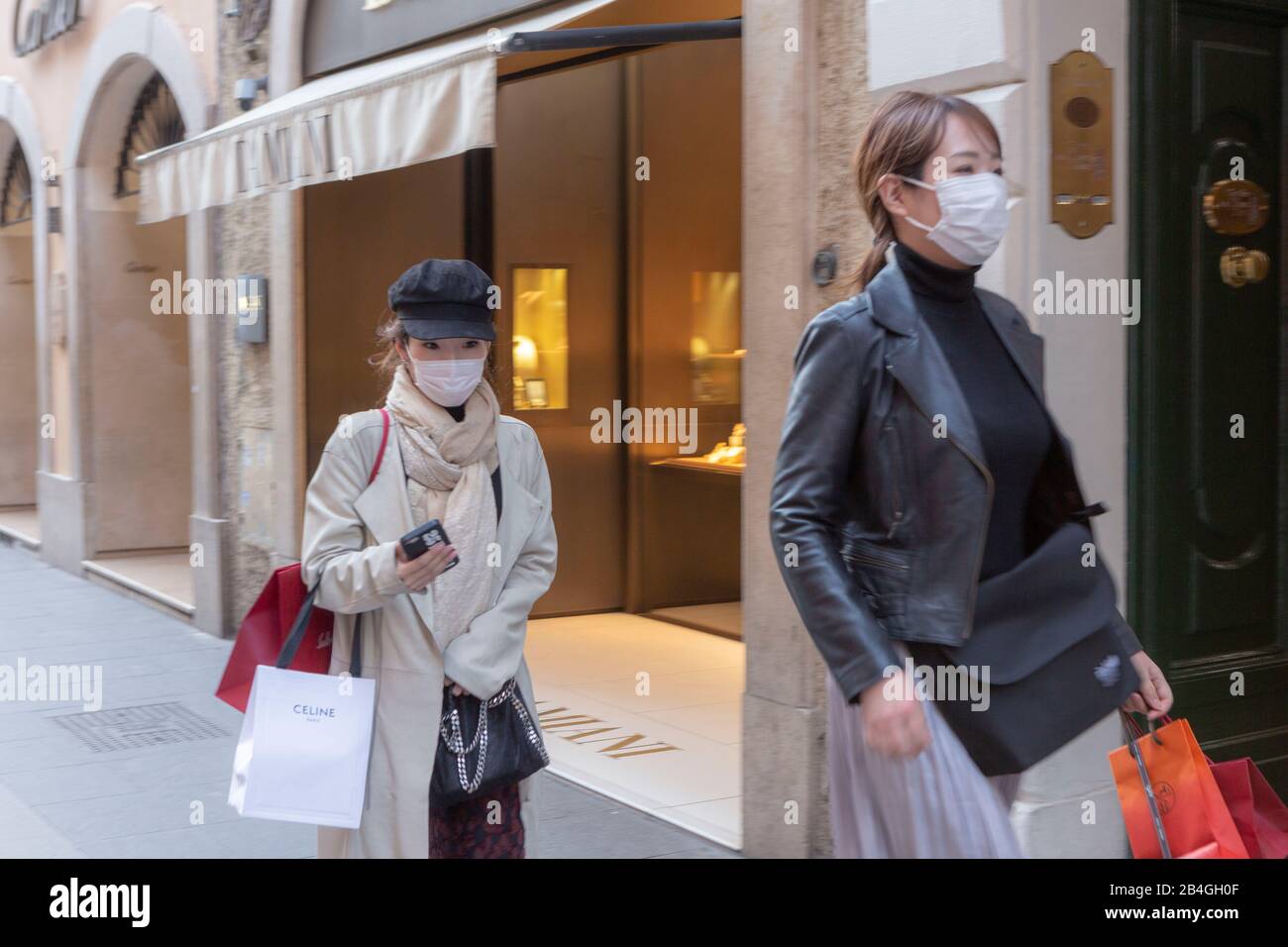 Two young Oriental women wearing surgical face masks against flu in the fashionable Via Condotti in Rome Stock Photo