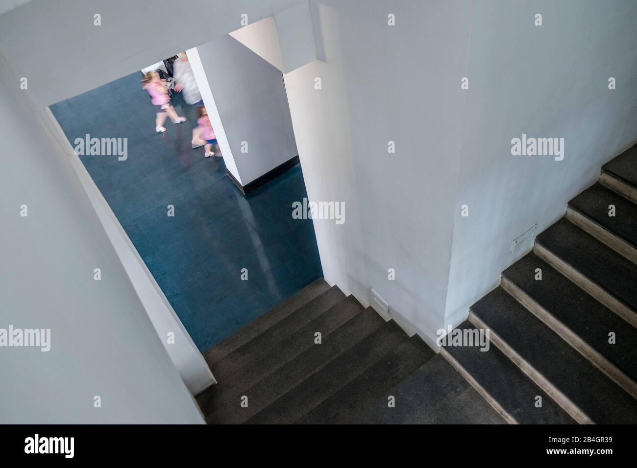 Architecture, down a staircase into a hallway, blurred people passing by Stock Photo