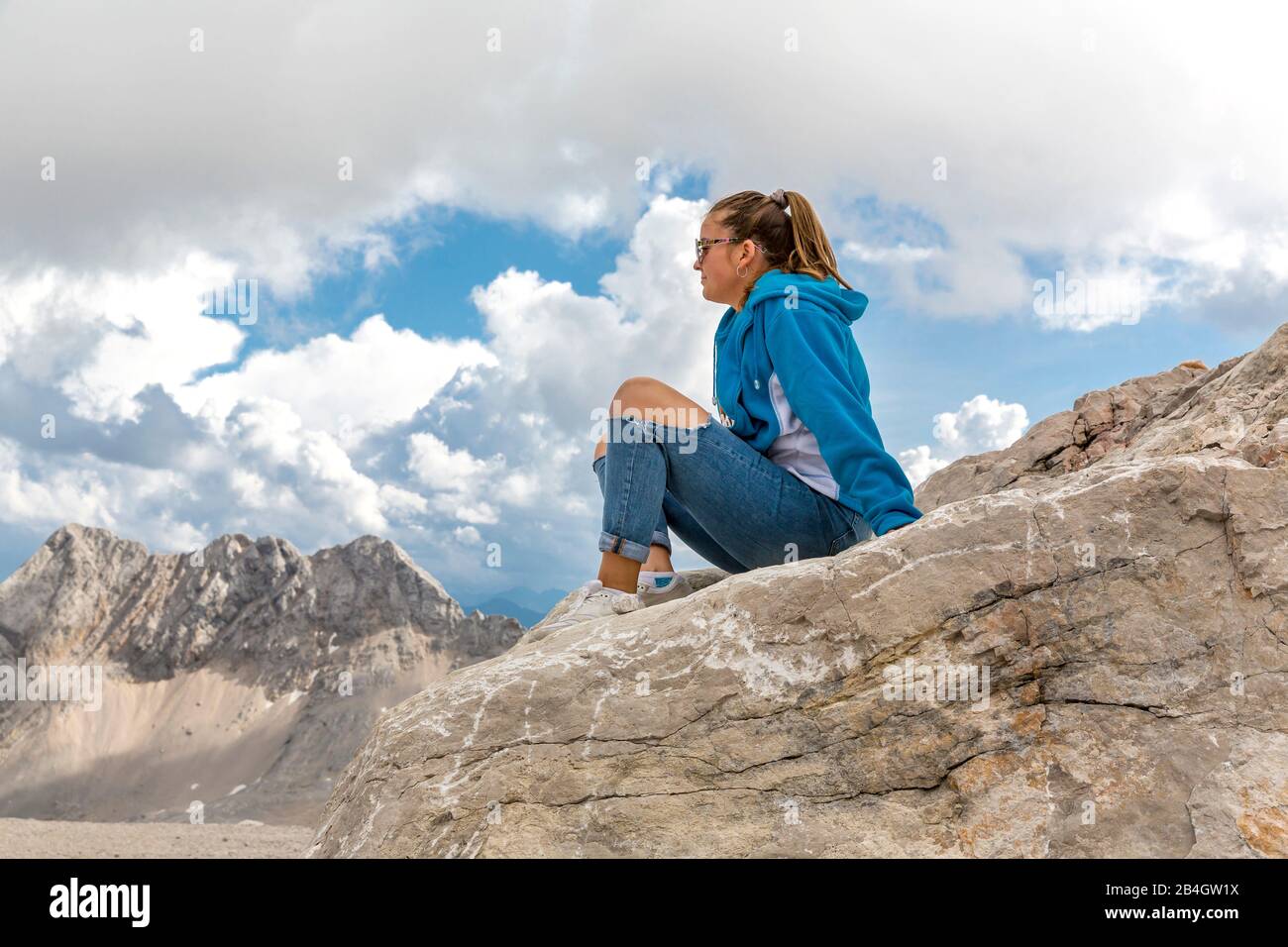 Junge Frau sitzt auf Felsen, Zugspitzplatt, Zugspitze, Garmisch-Partenkirchen, Wettersteingebirge, Alpen, Oberbayern, Bayern, Deutschland, Europa Stock Photo