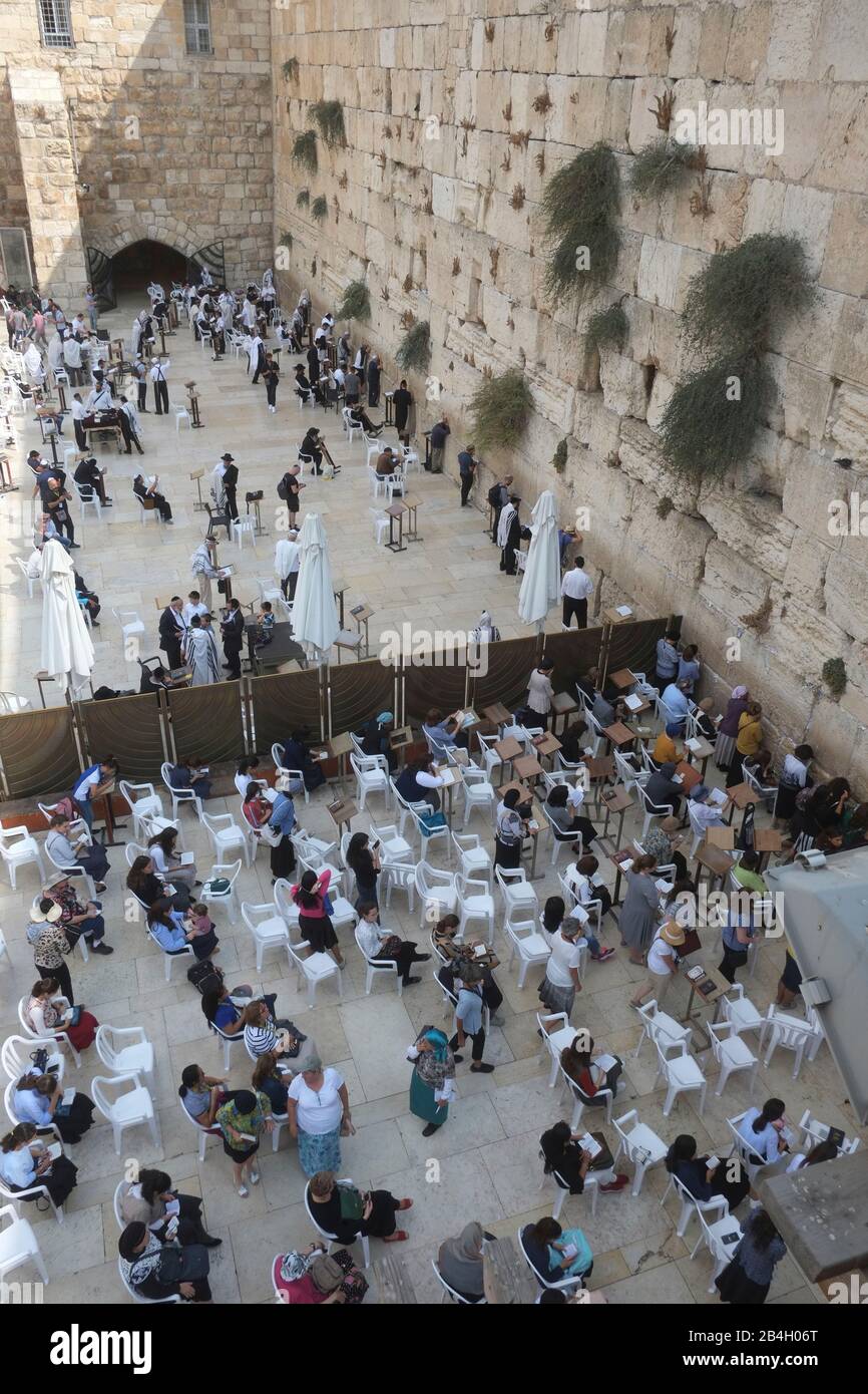 Men and women pray separately at Western Wall. The Western Wall, Wailing Wall, known in Islam as the Buraq Wall, is an ancient limestone wall in the Old City of Jerusalem. It is a relatively small segment of a far longer ancient retaining wall, known also in its entirety as the 'Western Wall' Stock Photo