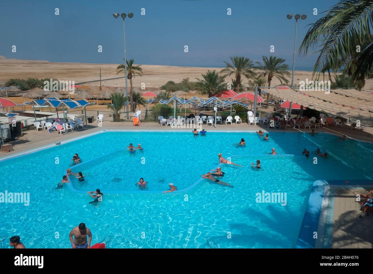 Swimming pool with Dead Sea in background in En Gedi oasis, Israel. Ein Gedi , literally 'spring of the kid (young goa' is an oasis and a nature reserve in Israel, located west of the Dead Sea, near Masada and the Qumran Caves. Ein Gedi was listed in 2016 as one of the most popular nature sites in the country Stock Photo