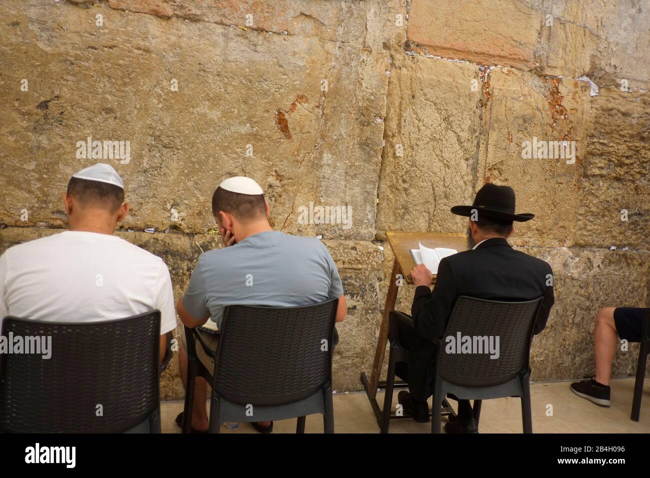 Jews praying during sabbath inside Western Wall. Western Wall in the Old City of Jerusalem, a place of prayer and pilgrimage sacred to the Jewish people. It is the only remains of the Second Temple of Jerusalem, held to be uniquely holy by the ancient Jews and destroyed by the Romans in 70 AD. The authenticity of the Western Wall has been confirmed by tradion, history, and archaeological research; the wall dates from about the 2nd century BC Stock Photo