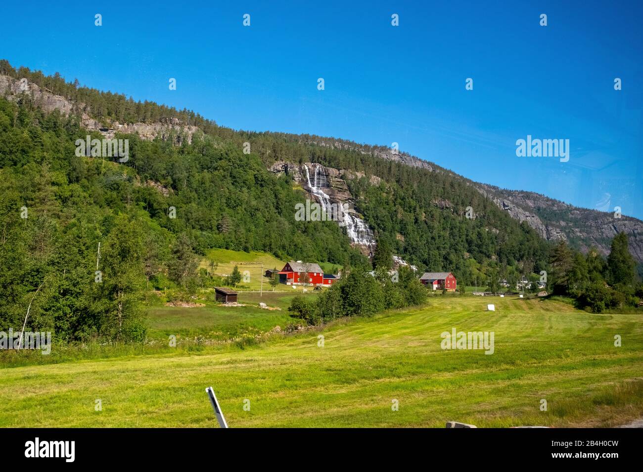 red mountain huts, railway ride with the Flambahn, meadows, trees, waterfall, mountains, blue sky, Skulestadmo, Hordaland, Norway, Scandinavia, Europe Stock Photo