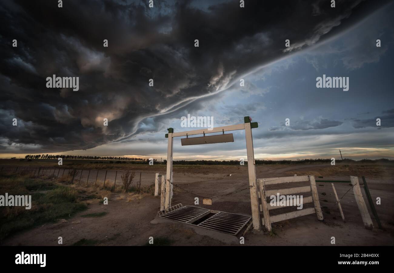 It's a big storm an tornado formation over the farm gate and cattle guard Stock Photo