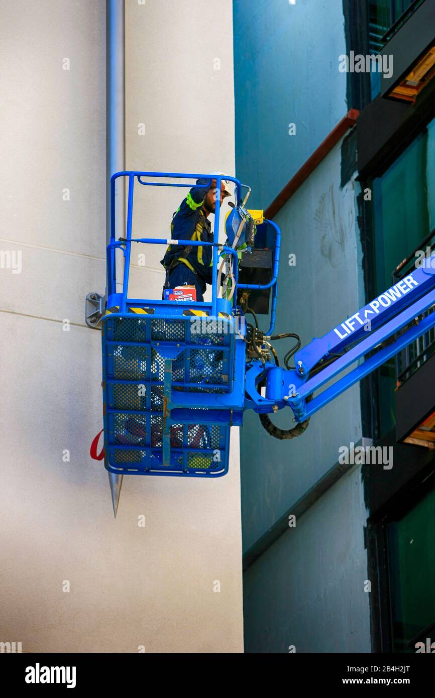 Man wearing a harness and safety work apparel in a cherrypicker on a building site in downtown Tucson AZ Stock Photo
