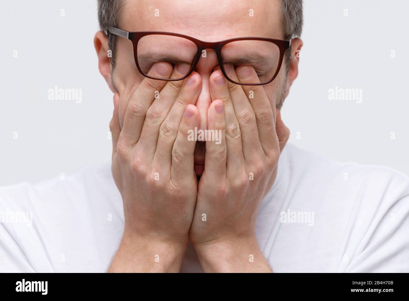 Sleepy man in eyeglasses rubbing her eyes, feels tired after working on laptop, isolated on white background. Overwork, exhausted, chronic fatigue, me Stock Photo