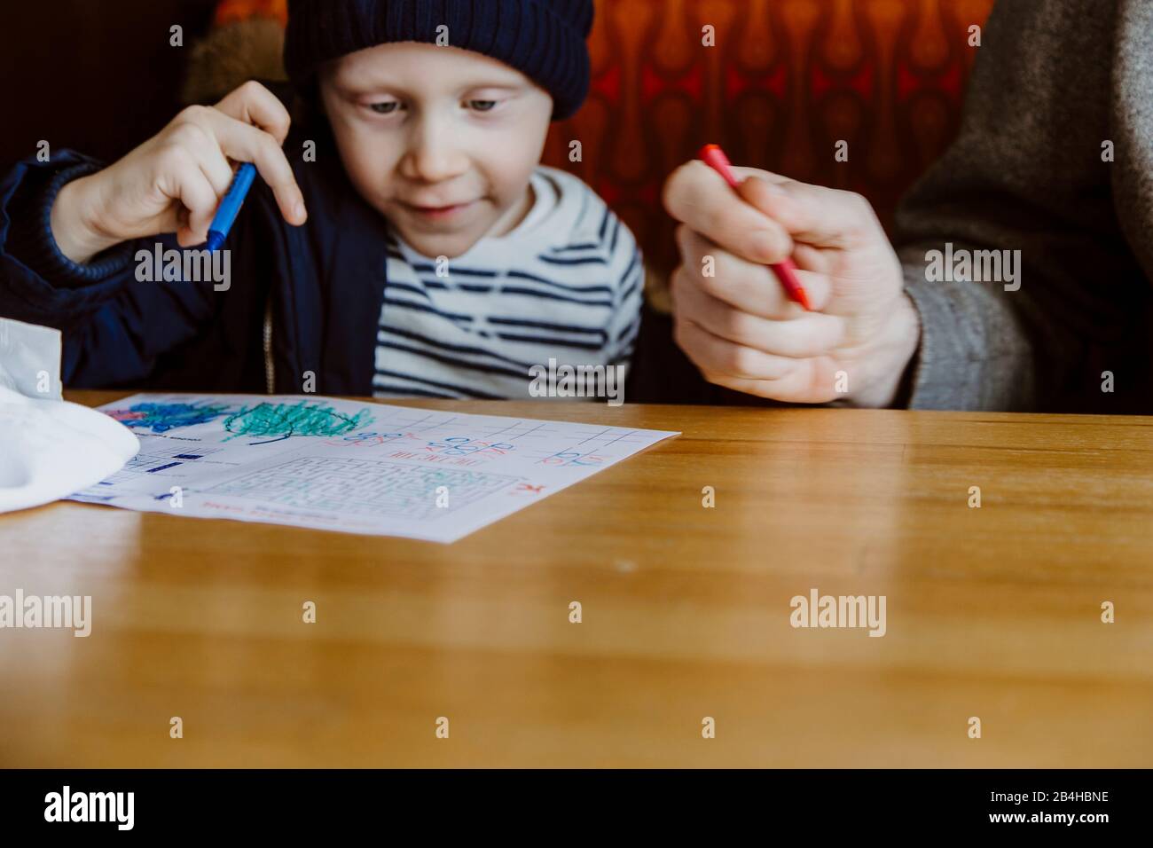 Father and son colouring in restaurant booth waiting for food Stock Photo
