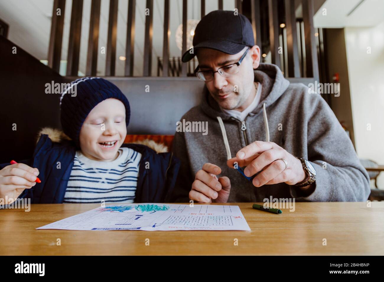 Father and son colouring in restaurant booth waiting for food Stock Photo