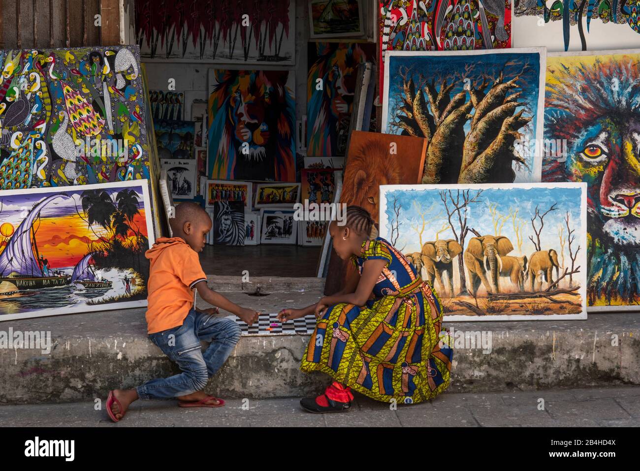 Destination Tanzania, Zanzibar Island: Impressions from Stone Town. Two children playing a board game in front of an art shop. Stock Photo