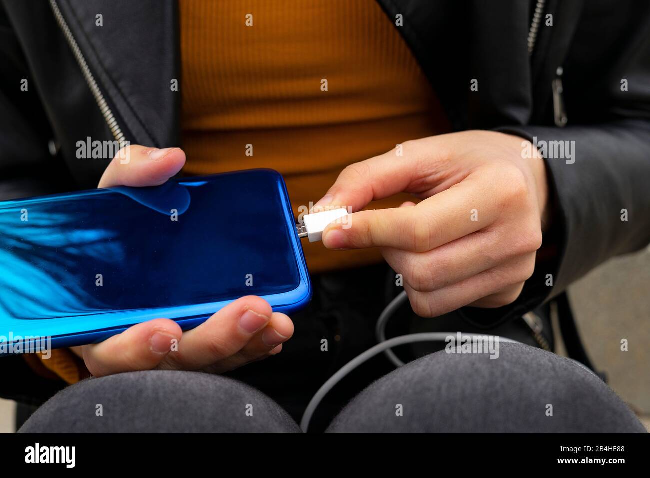 Hand connecting Micro USB cable to the mobile. Concept of charging the mobile. Stock Photo