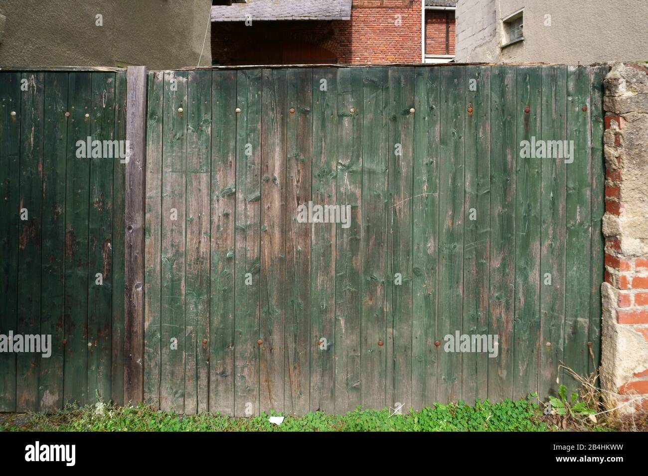 An old wooden fence with faded paint and rusty hinges. Stock Photo