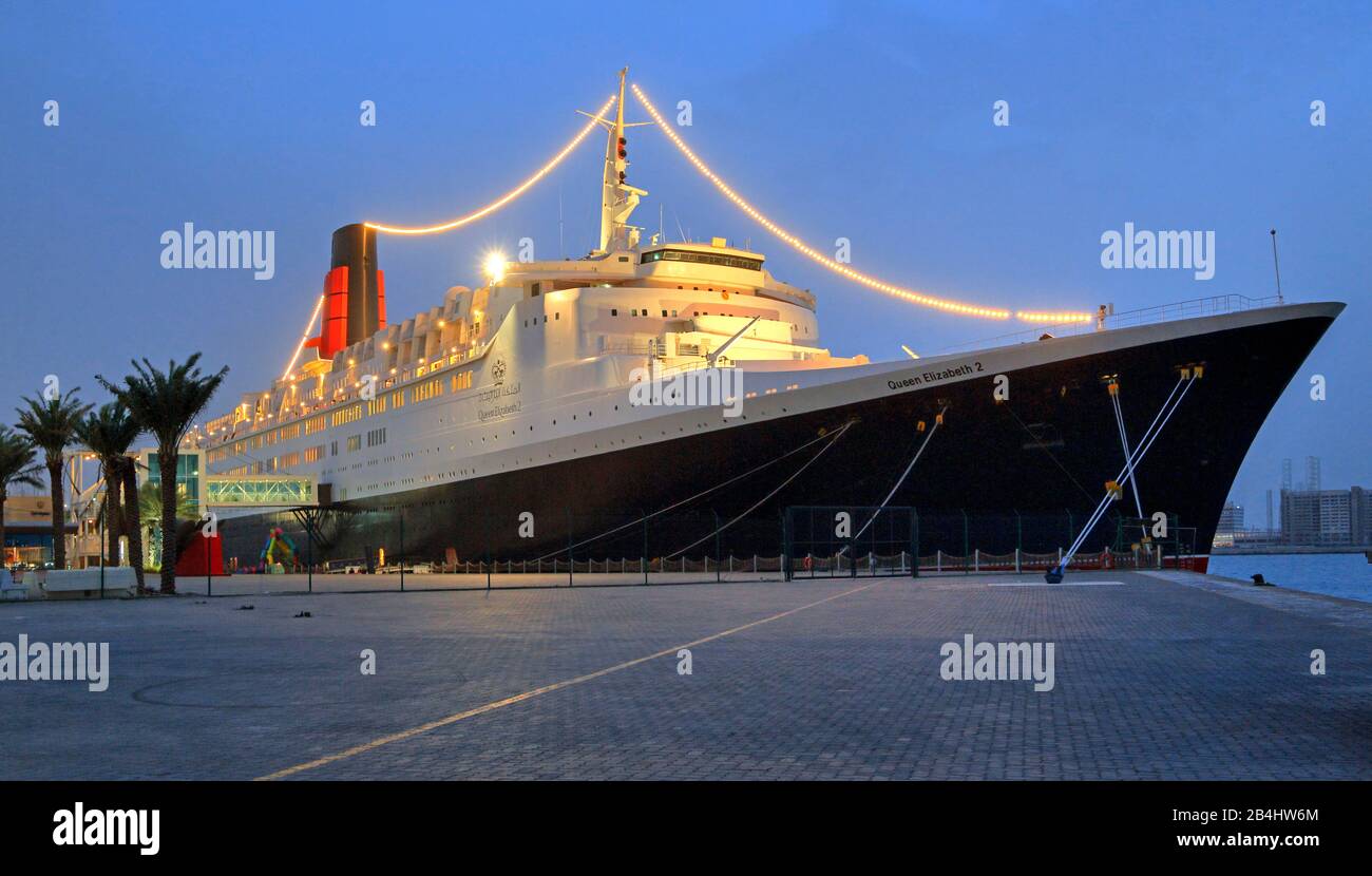 Illuminated hotel and museum ship Queen Elizabeth 2 (QE2) at the pier at dusk, Dubai, Persian Gulf, United Arab Emirates Stock Photo