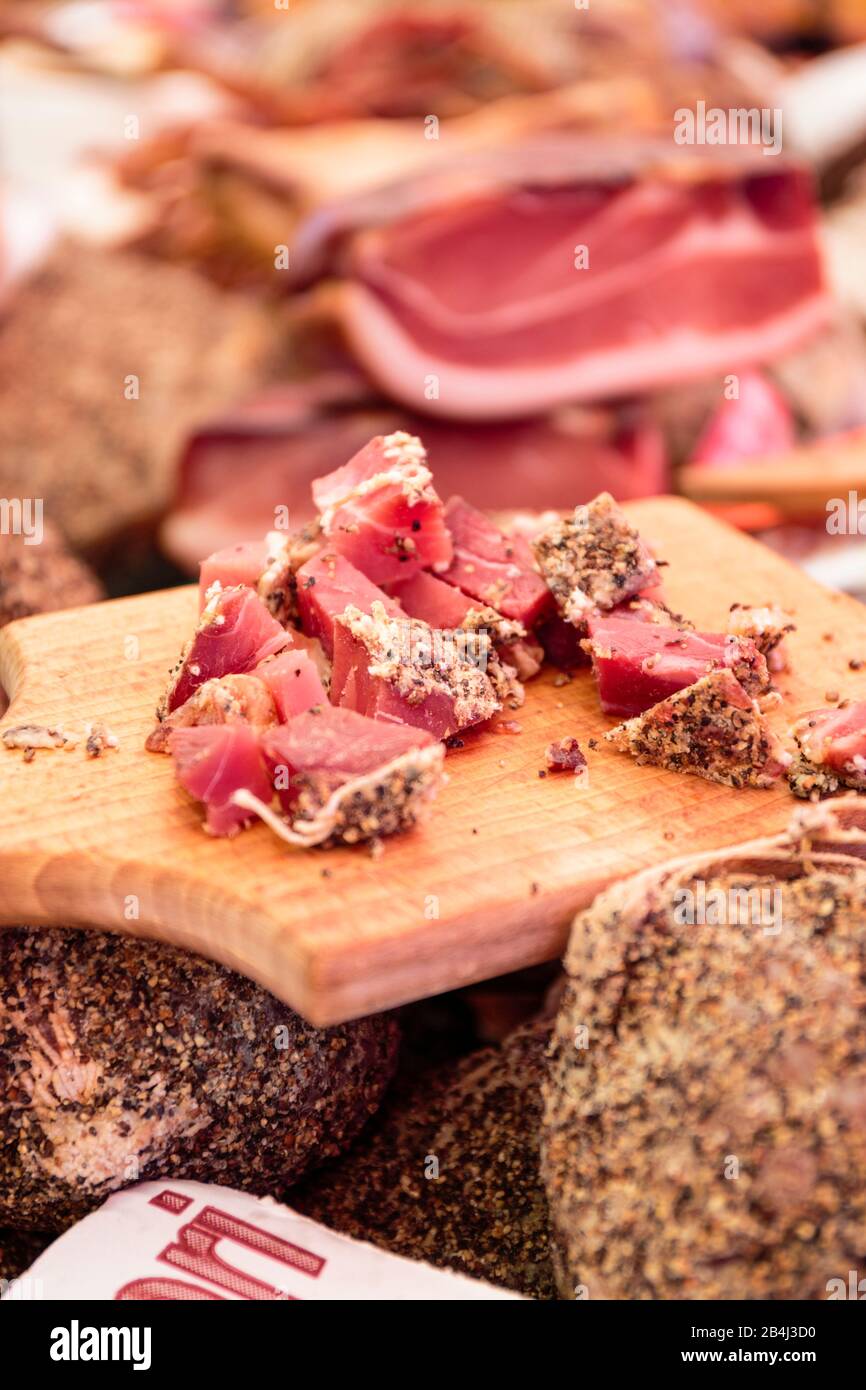 Europa, Italien, Piemont, Cannobio. Auf dem Wochenmarkt bietet ein Händler seine Wurst in kleinen Stücken zum Probieren an. Stock Photo