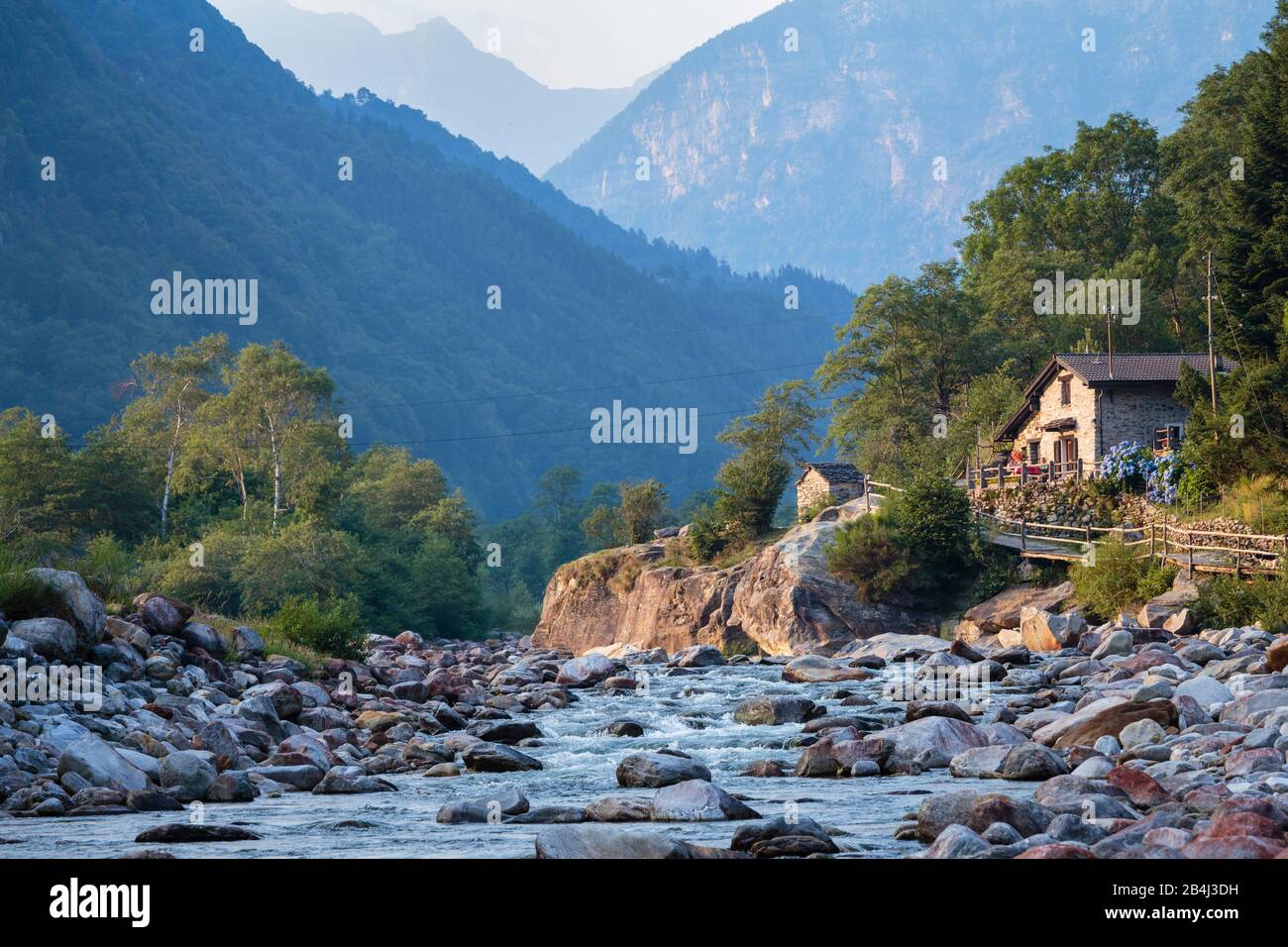 Europa, Schweiz, Tessin, Brione. Zwei Frauen sitzen in der kleinen Ebene von Brione vor typischen, idyllisch gelegenen Verzascahaus. Im Hintergrund ve Stock Photo