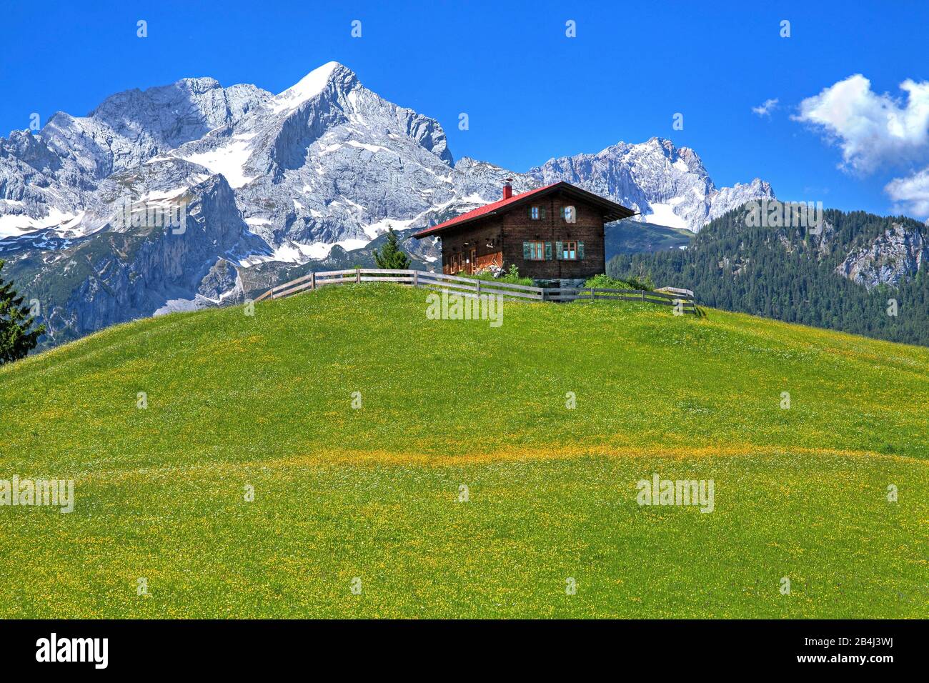 Mountain meadow with mountain hut on the Eckbauer 1237m against Alpspitze 2628m and Zugspitze 2962m in the Wetterstein Mountains, Garmisch-Partenkirchen, Loisachtal, Werdenfelser Land, Zugspitzland, Upper Bavaria, Bavaria, Germany Stock Photo